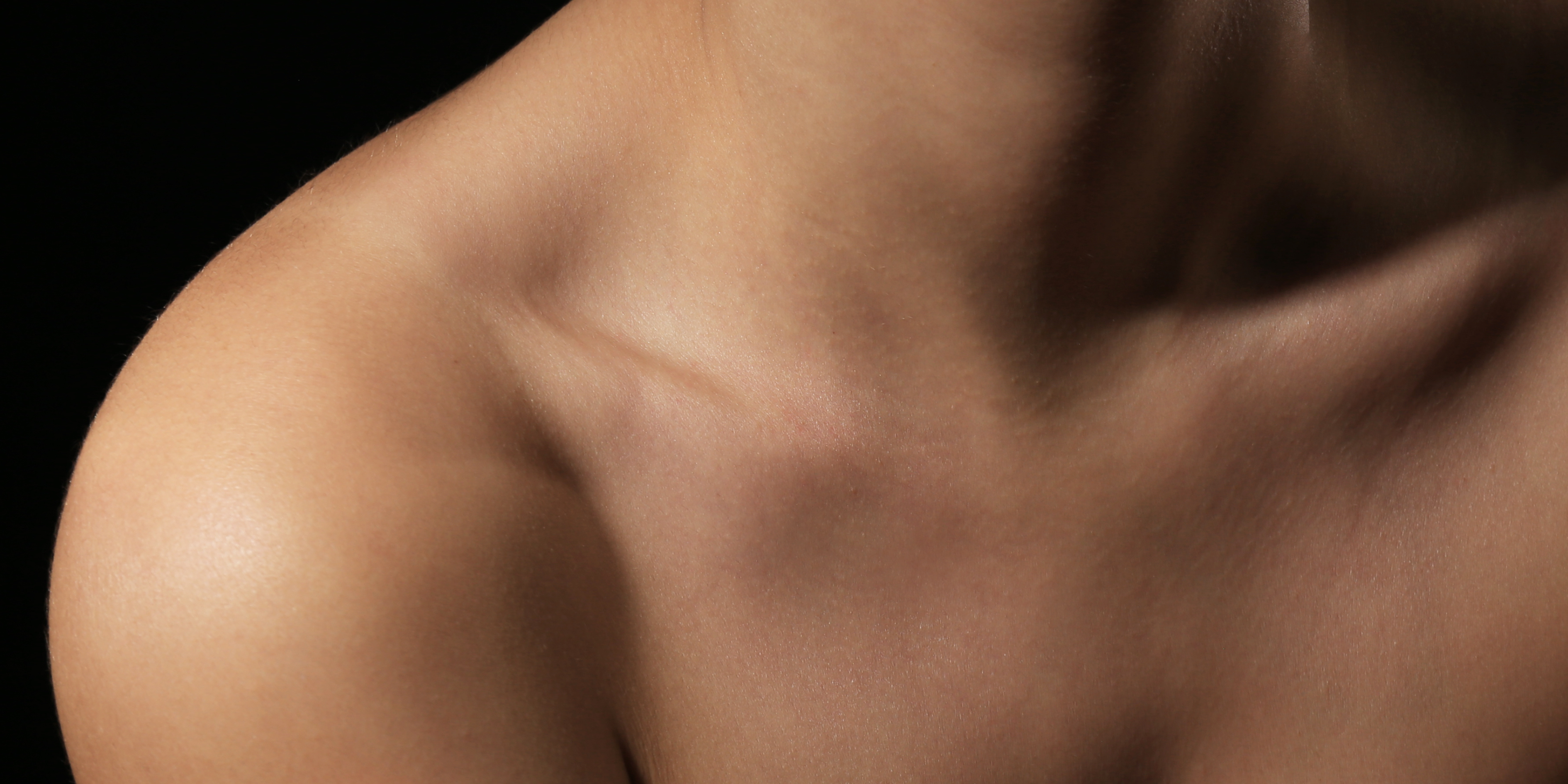 Close-up of a person's shoulder and neck with a black background
